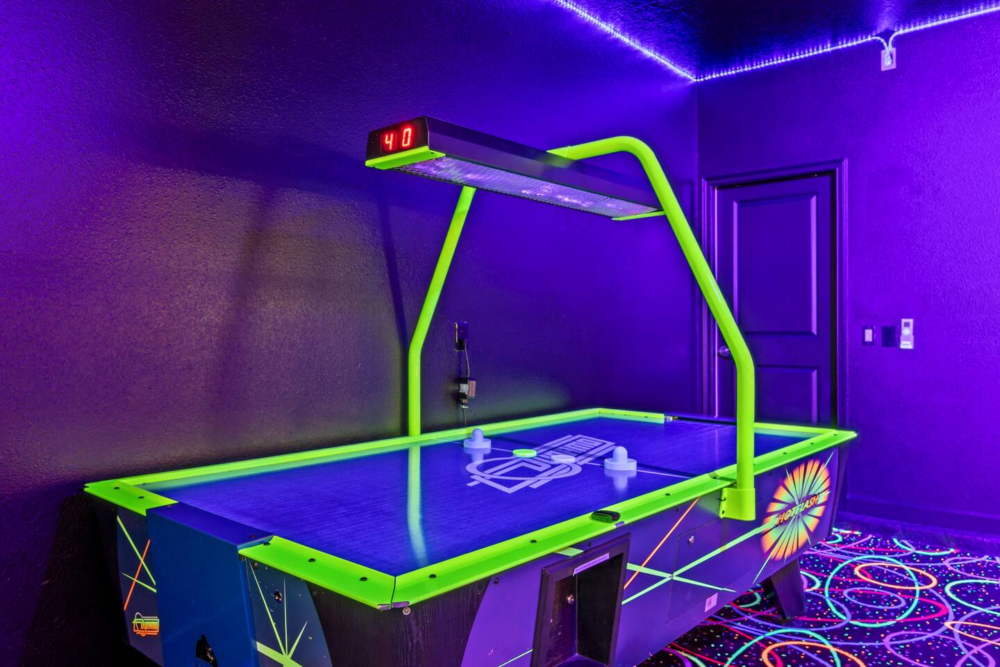 Air hockey table with electronic scoreboard in the blacklight game room