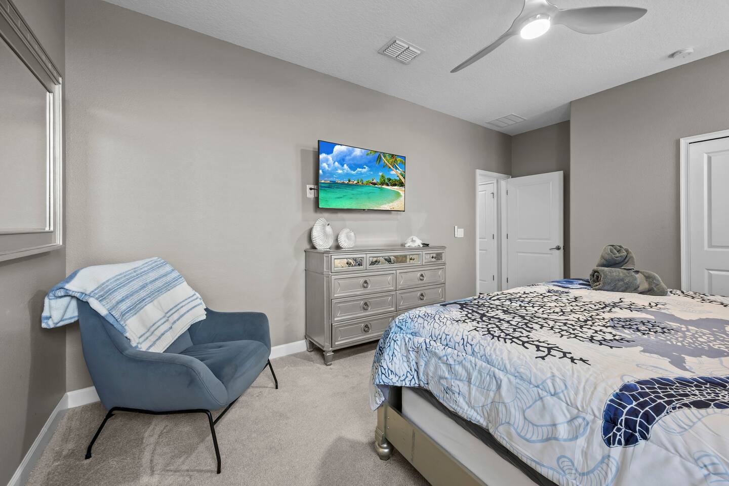 Primary bedroom sitting corner with accent chair, silver dresser, and wall-mount