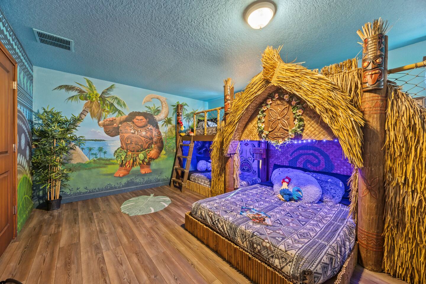Moana suite with Maui wall mural, tiki totem posts, and the hut bed lit in purpl