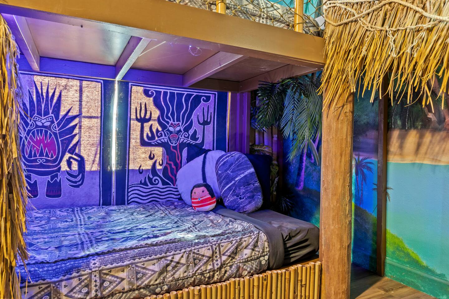 Lower bunk nook with island-print bedding and glowing tapestry backdrop