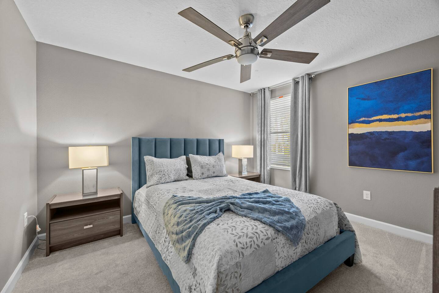 Queen bedroom with teal channel-tufted headboard and abstract blue artwork