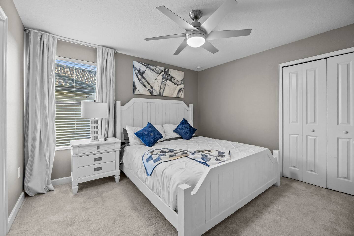 Bedroom with white plank-style bed frame, navy accent pillows, and double closet