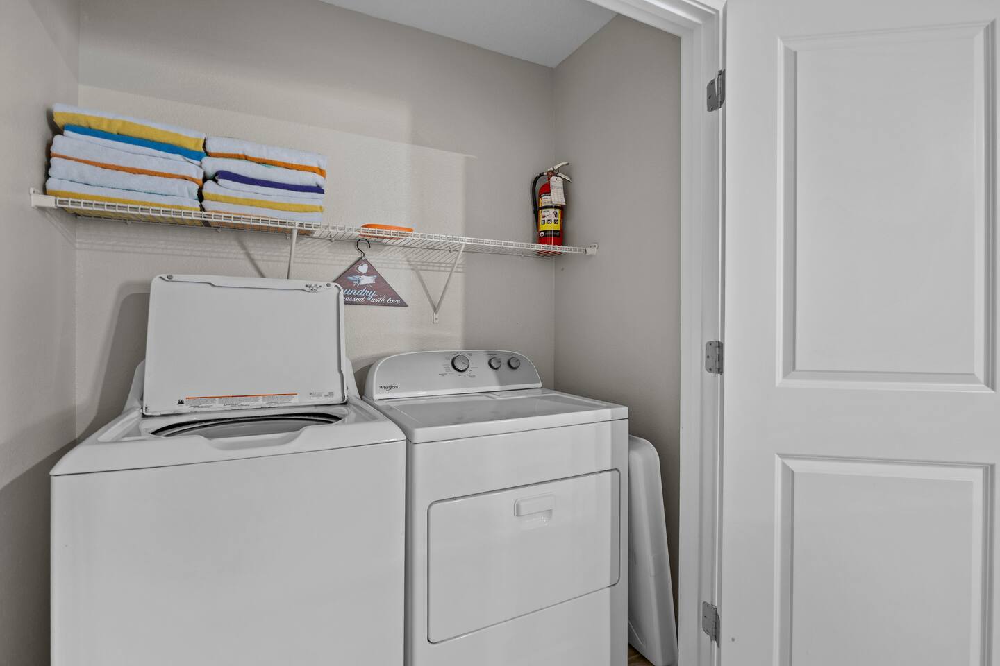 Laundry closet with full-size washer and dryer and shelf of beach towels