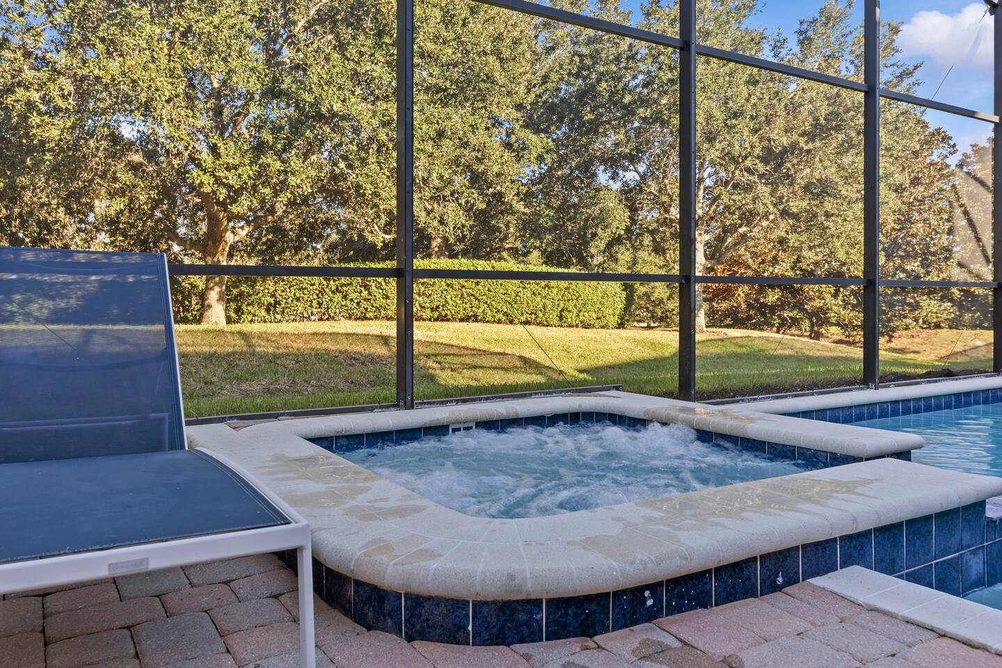 Spa close-up with jets running and greenbelt view through the screen enclosure