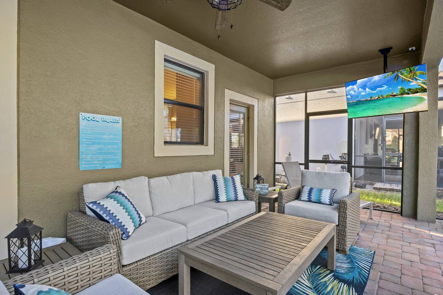 Lanai lounge set with cushioned sofa and chairs, ceiling-mounted TV, and posted 