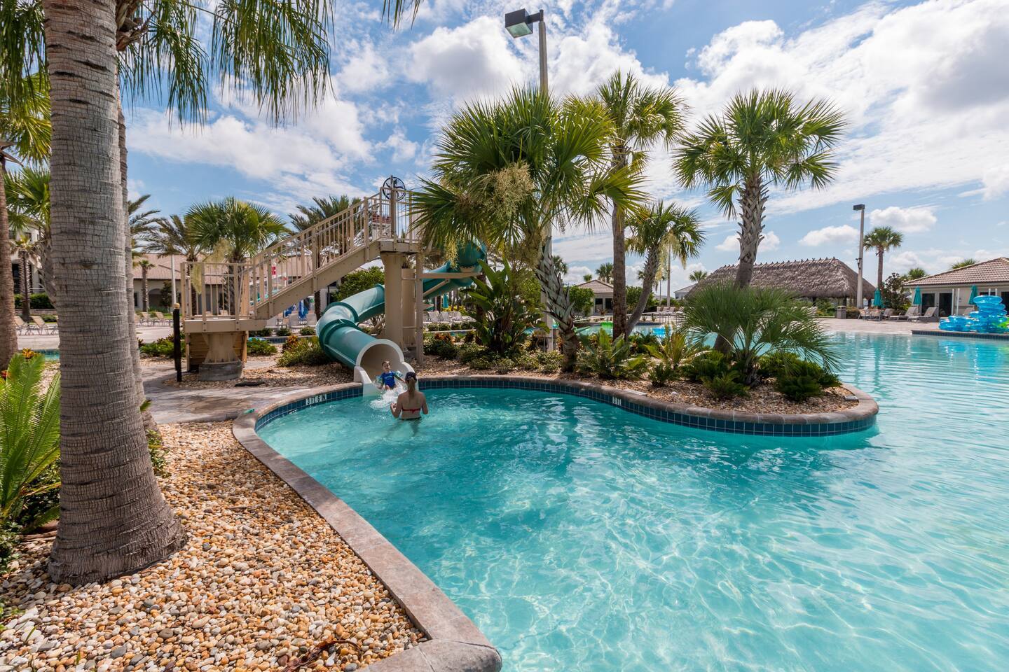 Resort water-play area with water slide and palm-lined lagoon pool