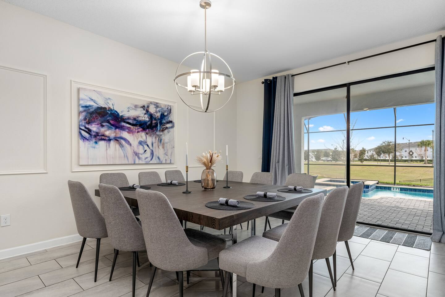 Dining room seating twelve with pool view and modern chandelier
