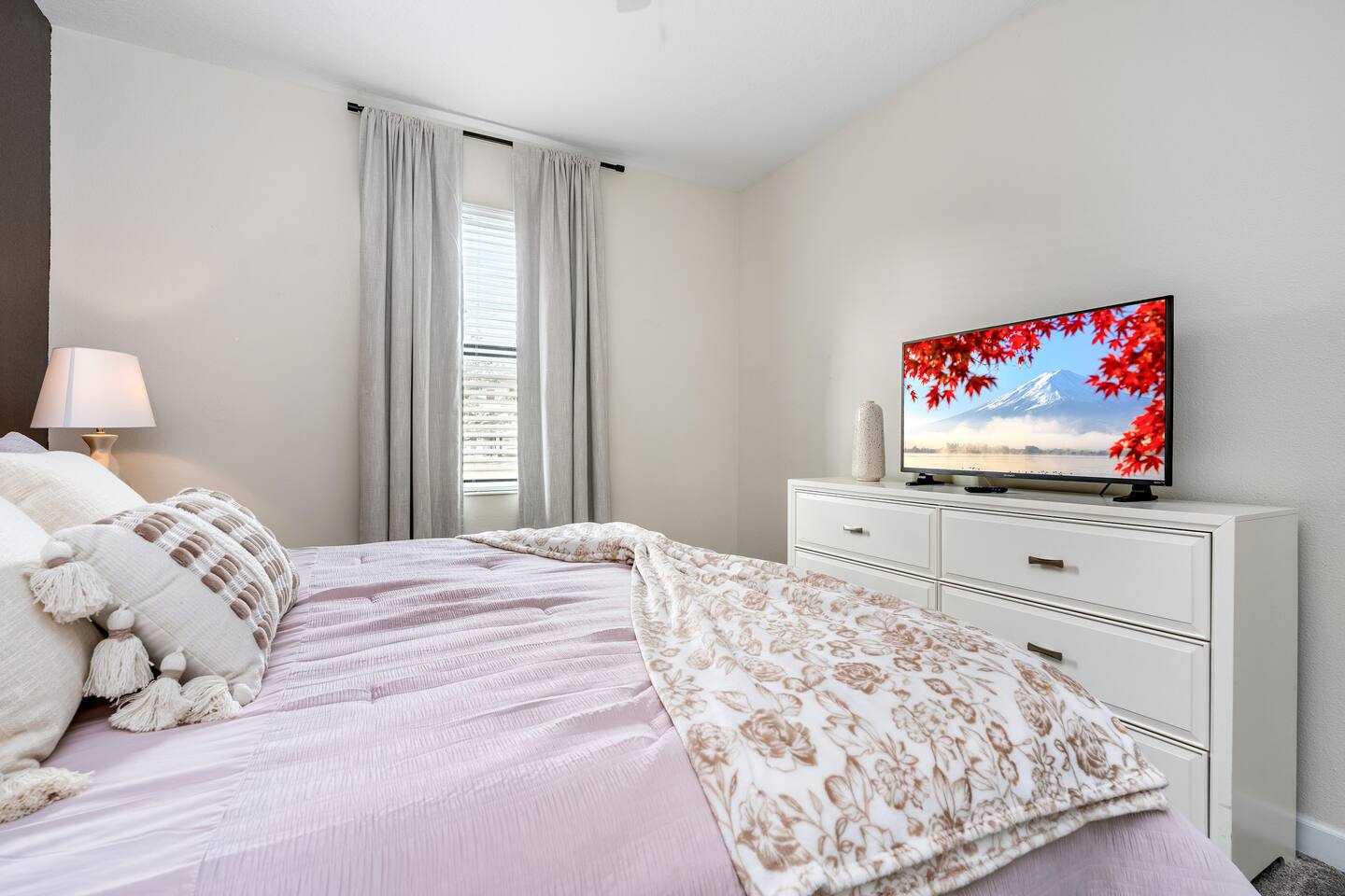 Bedroom with dresser, flat-screen TV, and soft pink bedding