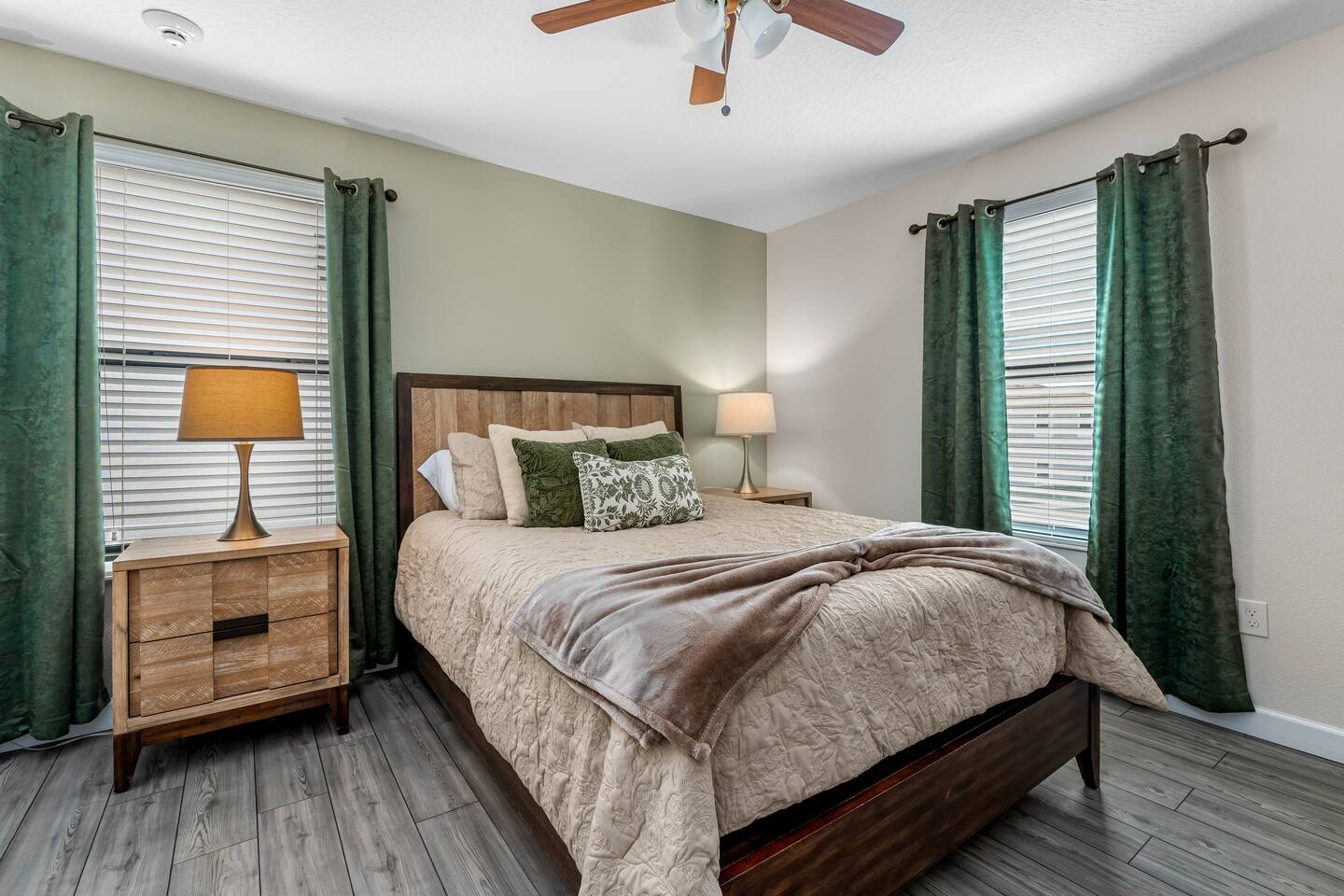 Queen bedroom with wood headboard and green curtains