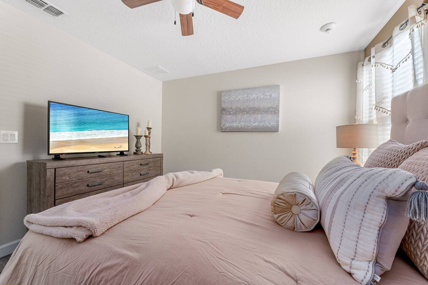 Bedroom with dresser, flat-screen TV, and blush bedding