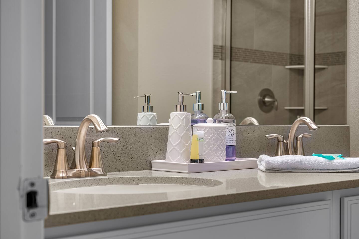 Bathroom vanity with toiletries, hand soap, and fresh towels