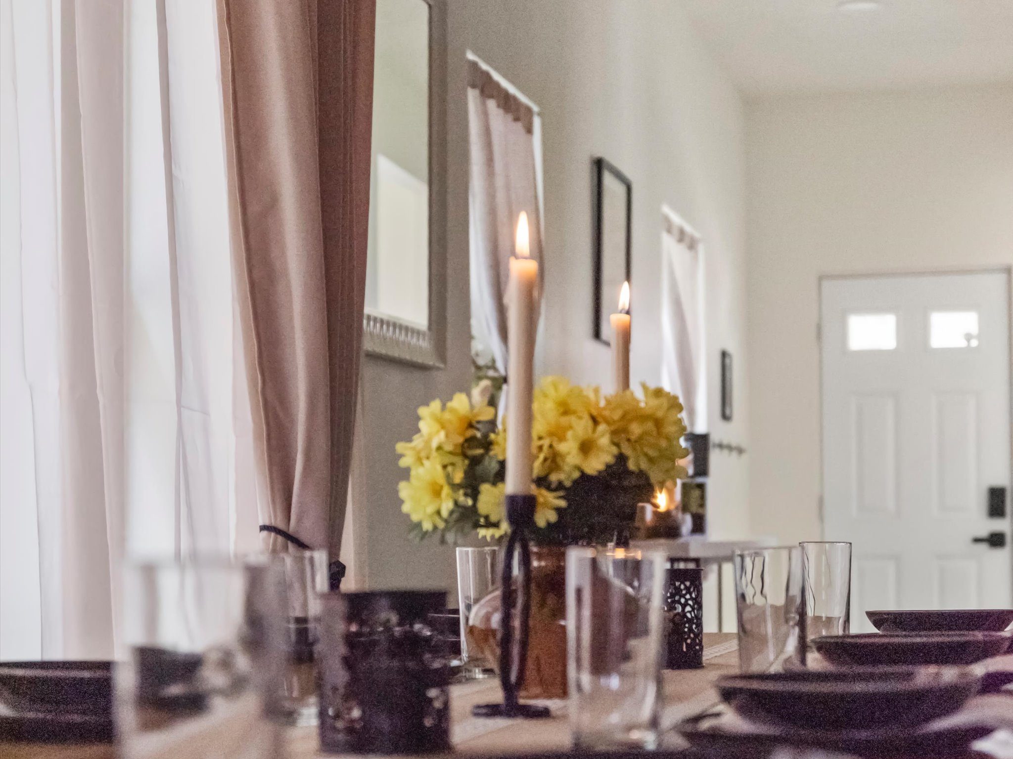 Dining table set with candlesticks and fresh flowers near the front entry