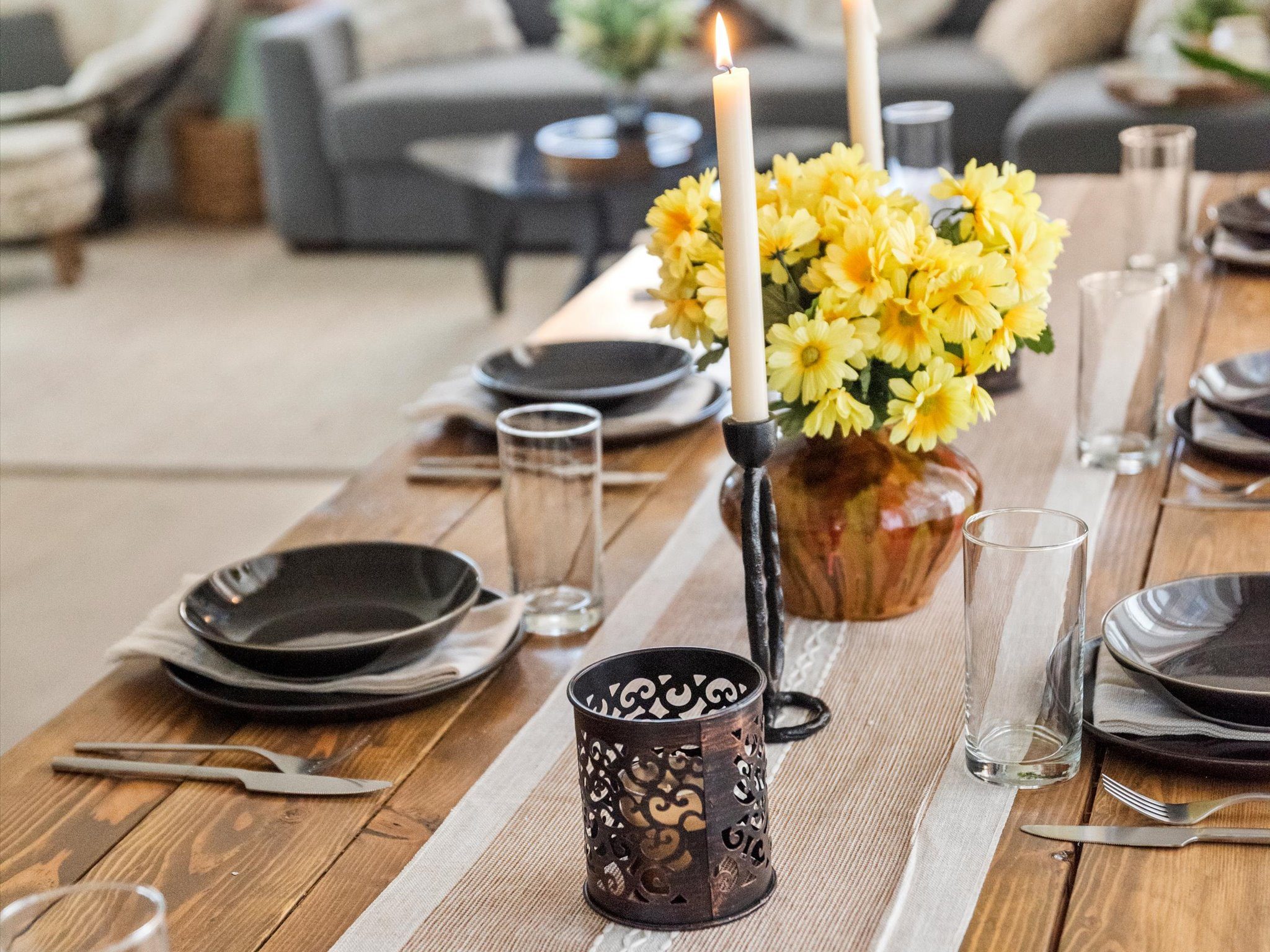 Table set with black dinnerware and a yellow floral centerpiece