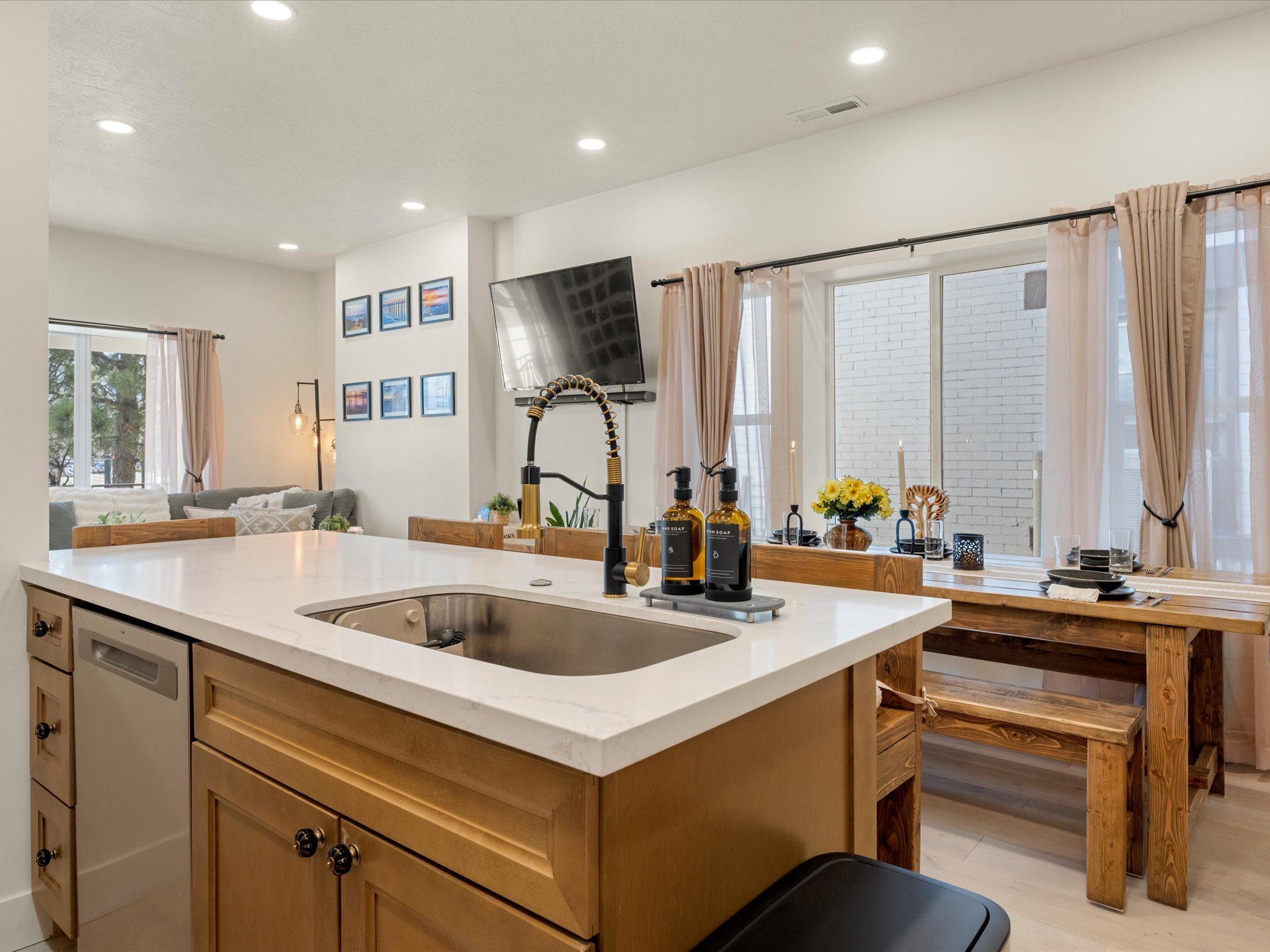 Kitchen island with sink alongside the farmhouse dining bench and living area