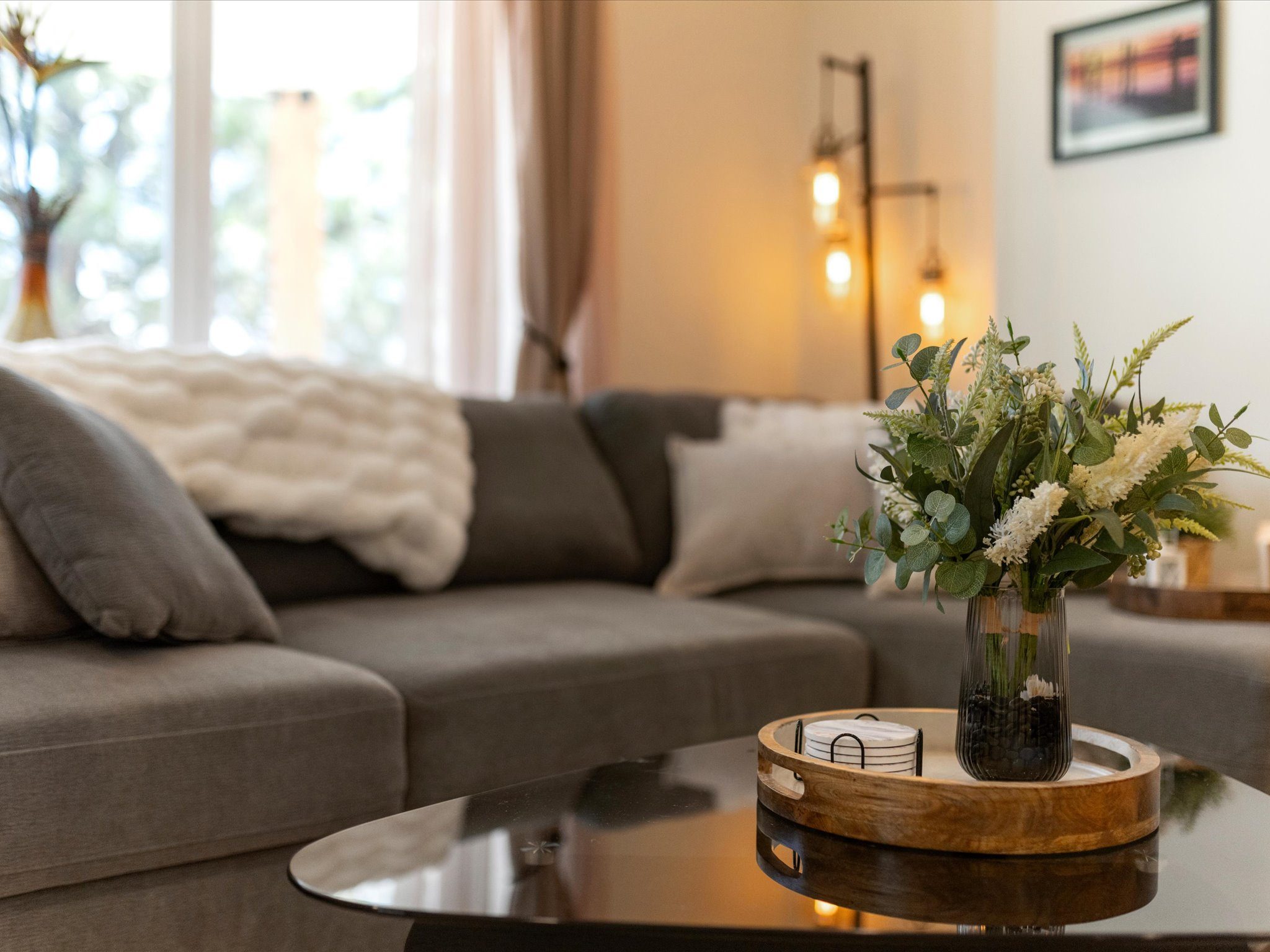 Living room seating with a glass coffee table and greenery accents