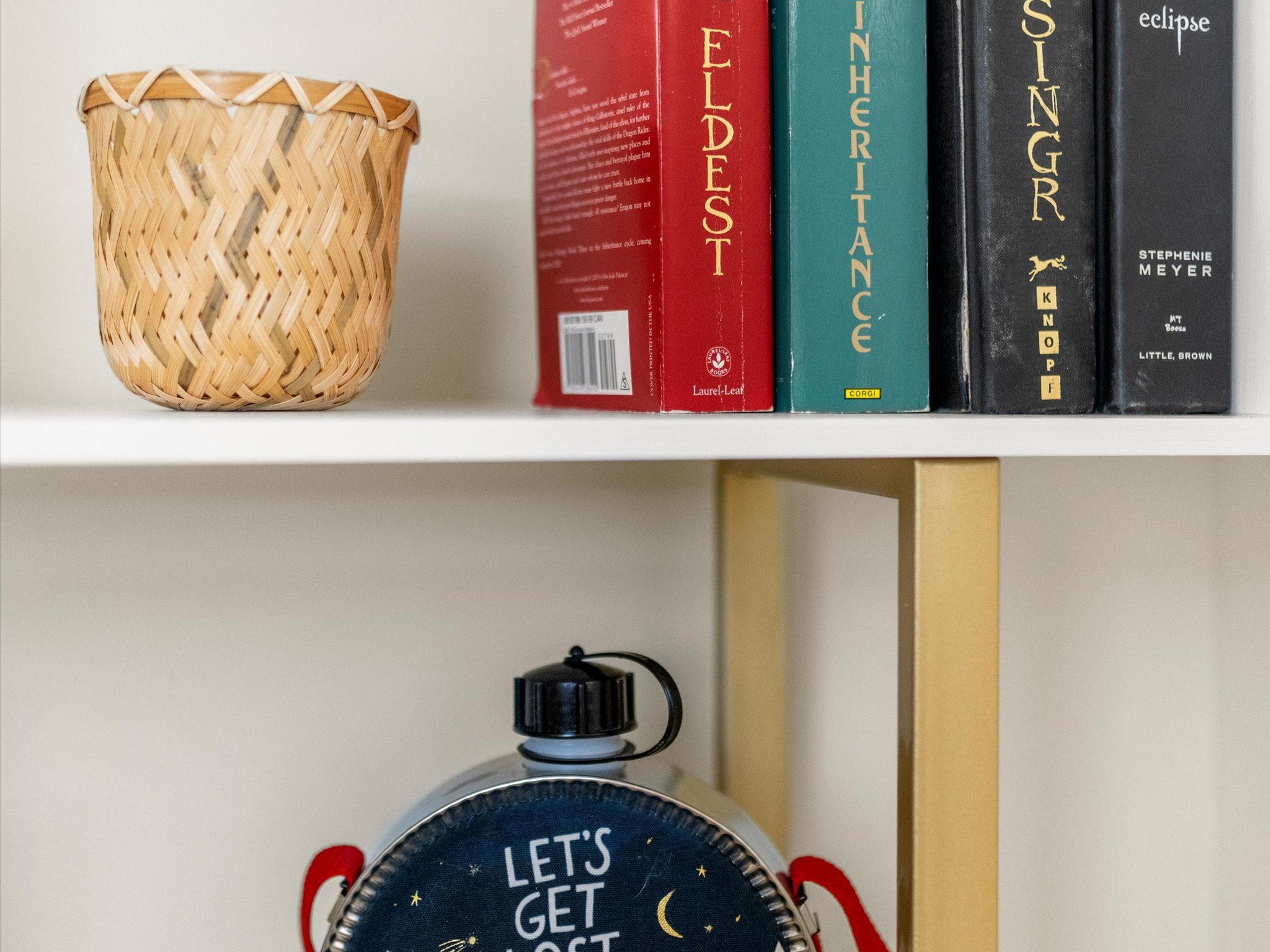 Bookshelf styled with novels and a decorative canteen