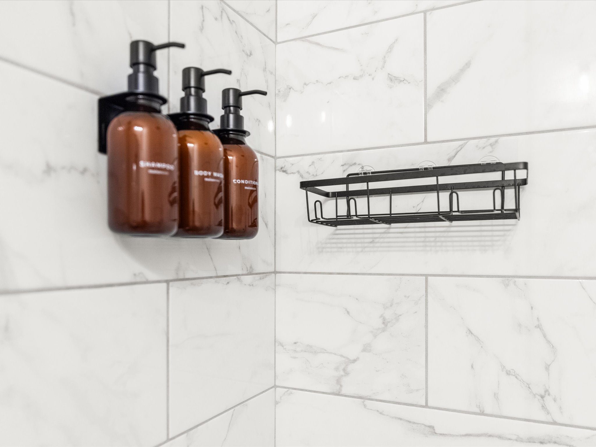 Marble-tiled shower with refillable shampoo, body wash, and conditioner
