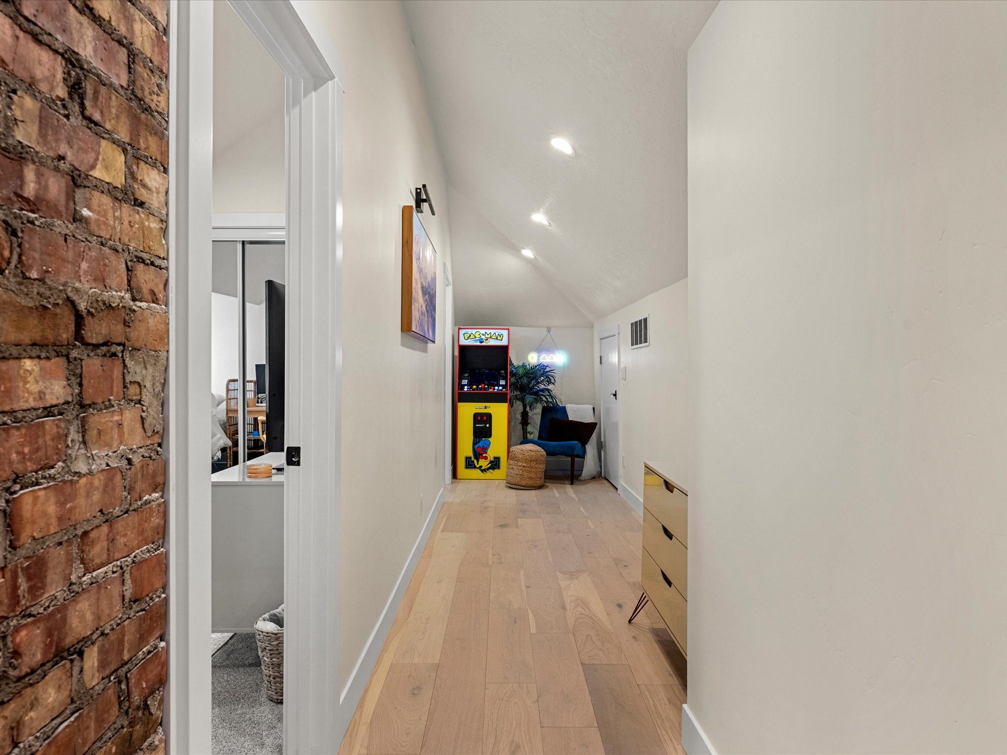 Upstairs hall with an exposed-brick accent leading to the arcade nook