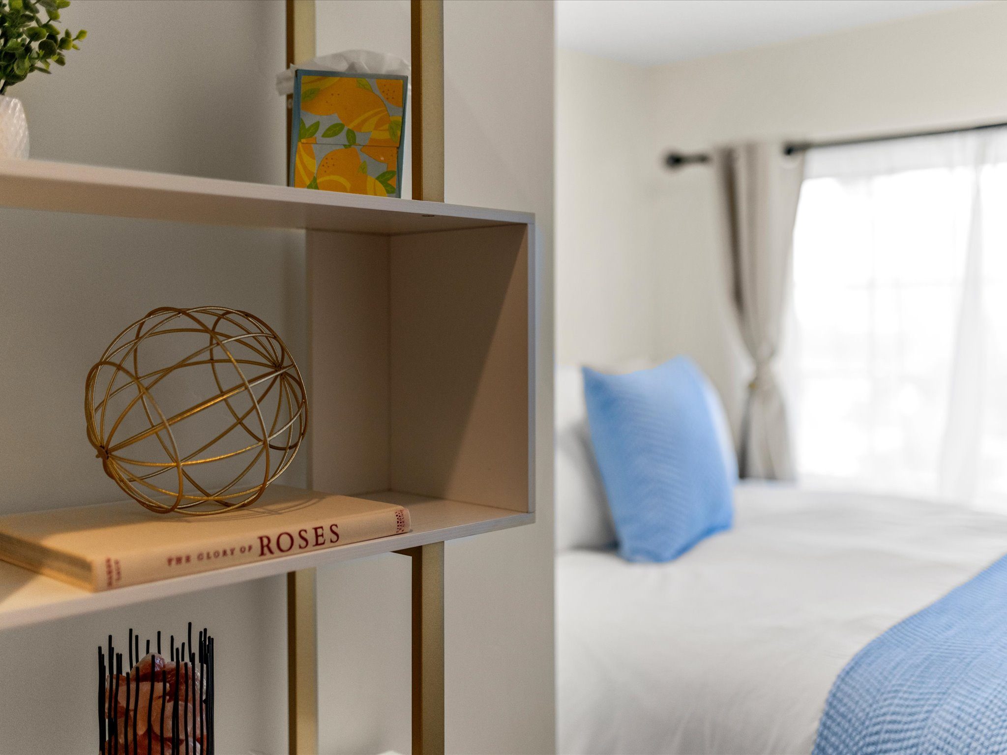Bedroom shelving styled with books and decor beside the bed