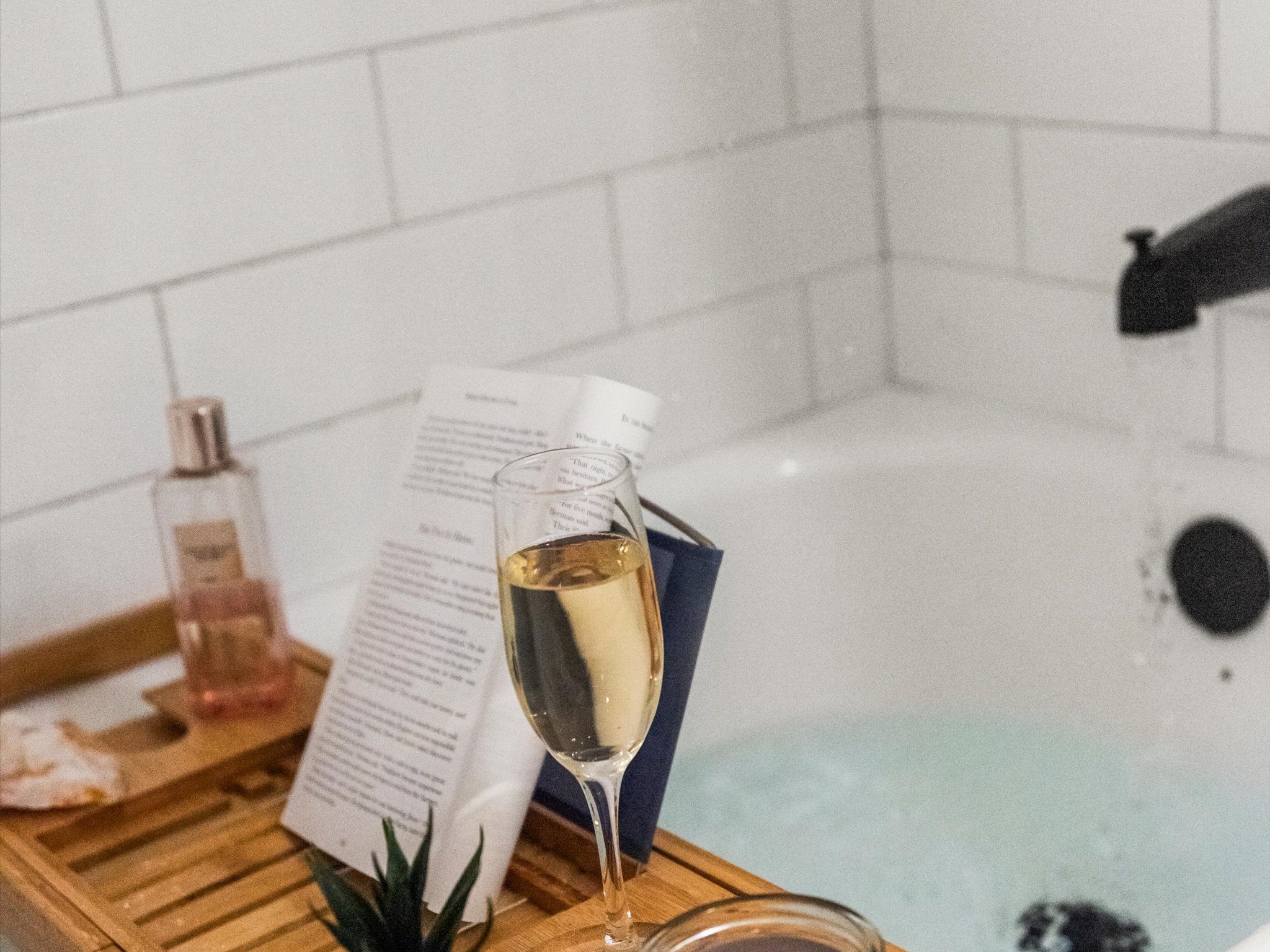 Soaking tub styled with a book and a glass of sparkling wine