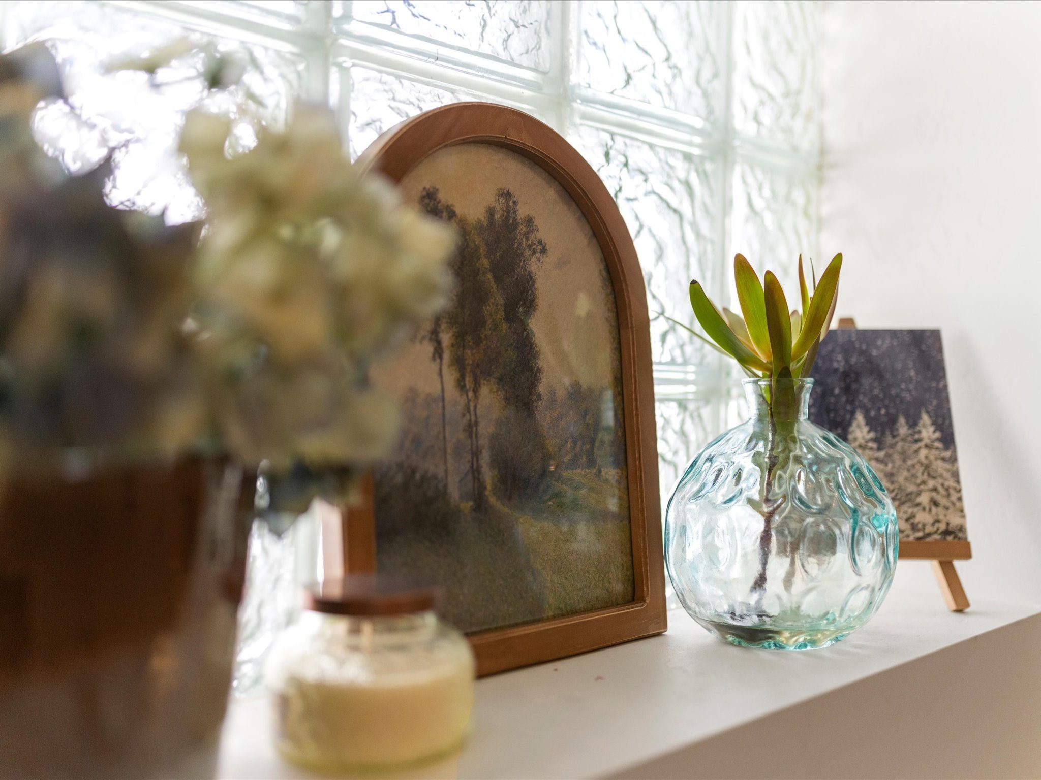 Styled shelf with framed art beside a glass-block window