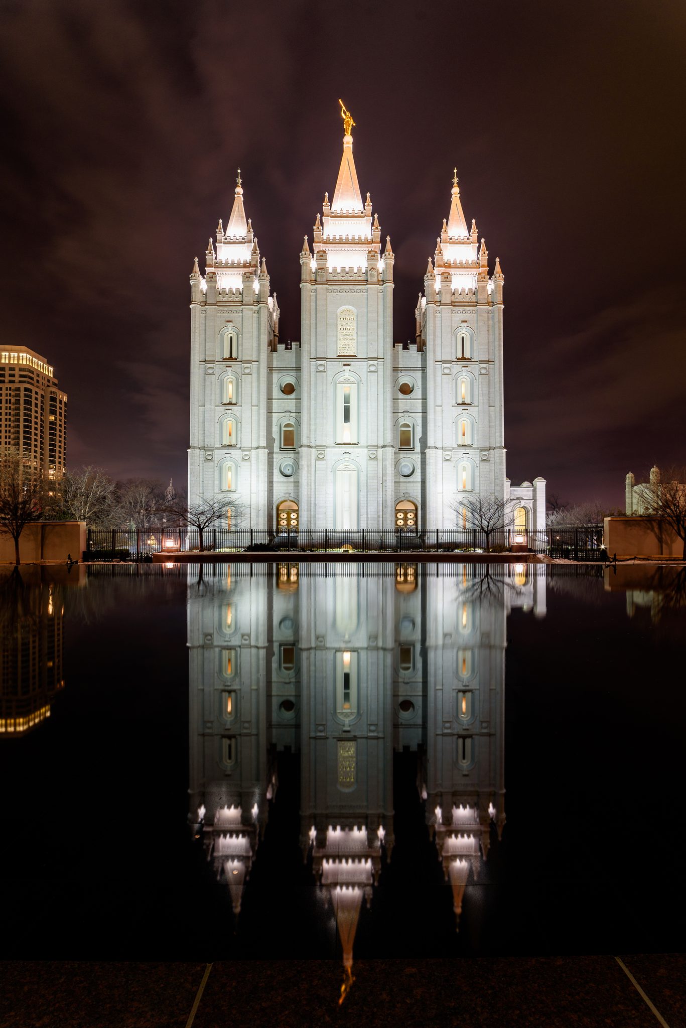 Salt Lake Temple illuminated at night with a reflecting-pool mirror image