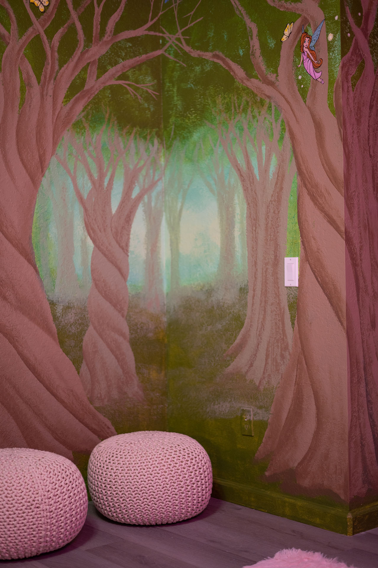 Misty enchanted-forest mural with knitted poufs in the fairytale bedroom.