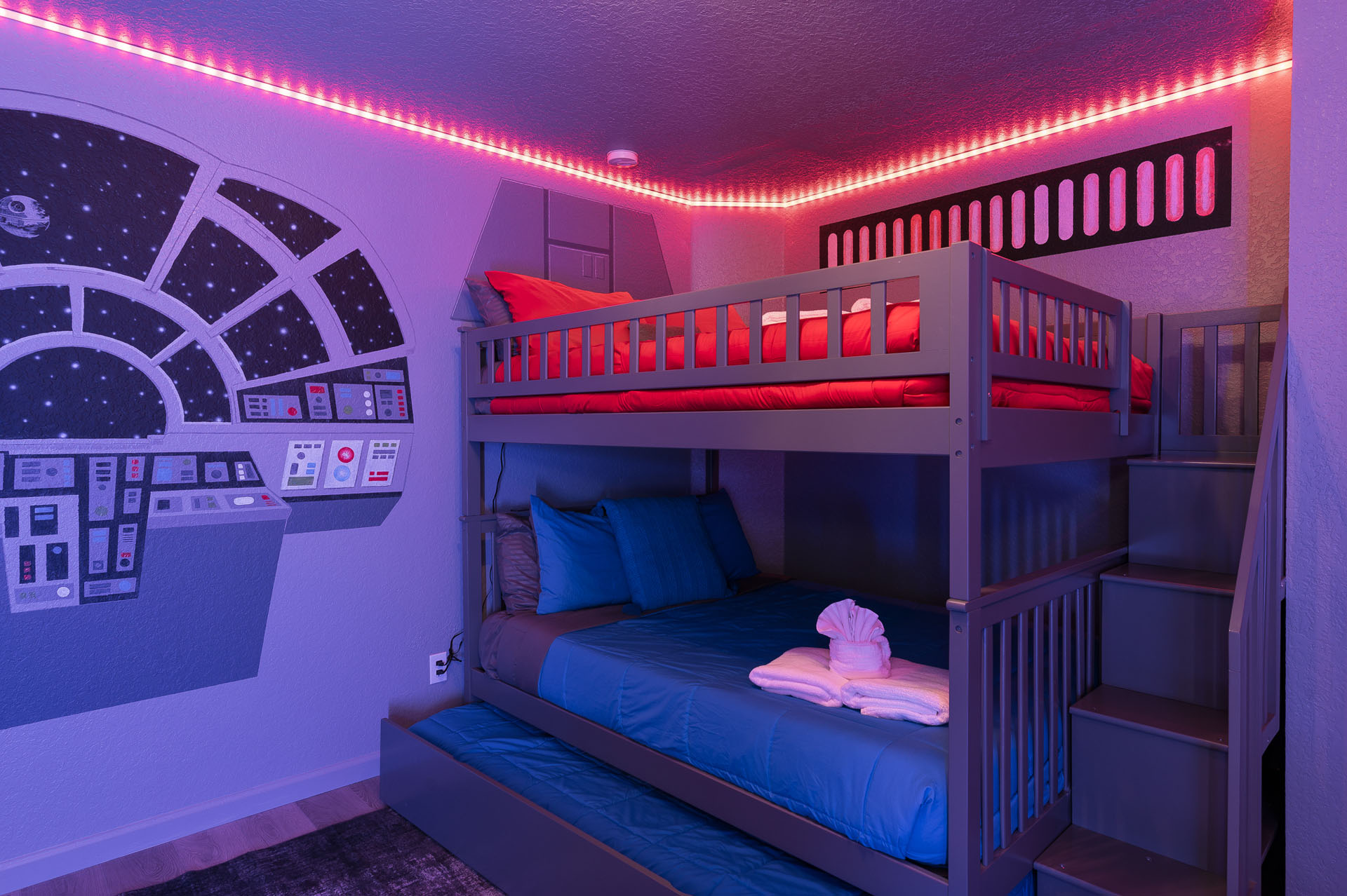 Bunk beds with a pull-out trundle beneath color-changing accent lighting in the 