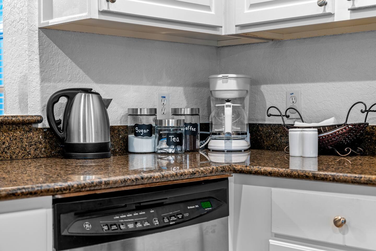 Coffee and tea station with kettle, coffee maker, and stocked canisters.