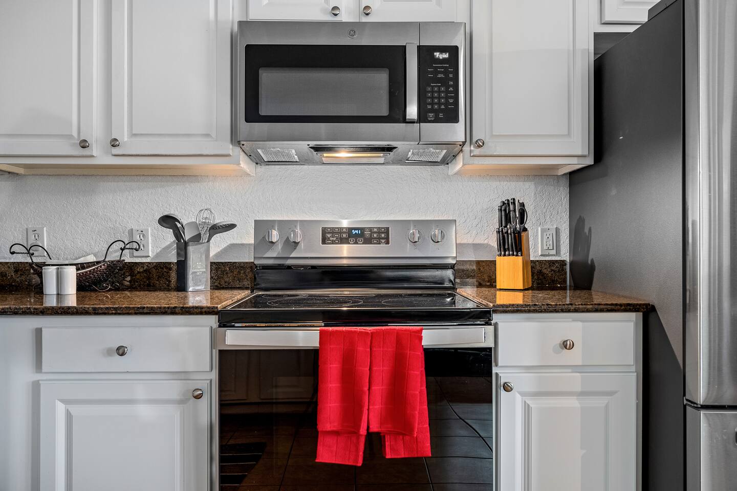 Electric range, microwave, and knife block ready for home-cooked meals.