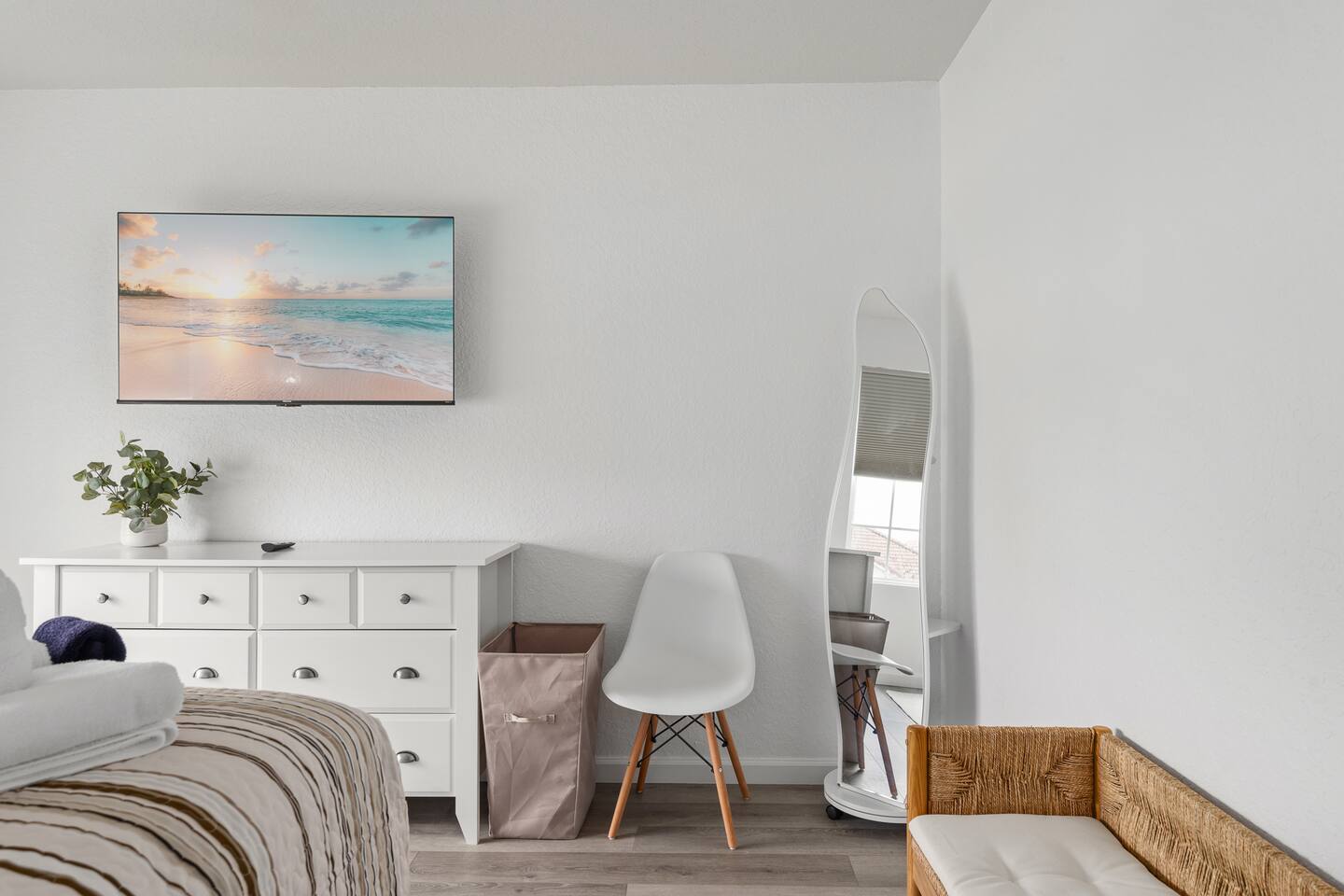 Beach-inspired king bedroom with full-length mirror and desk chair.