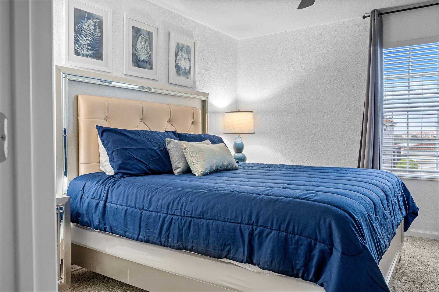 Champagne-toned king bed with navy comforter and matching nightstands.