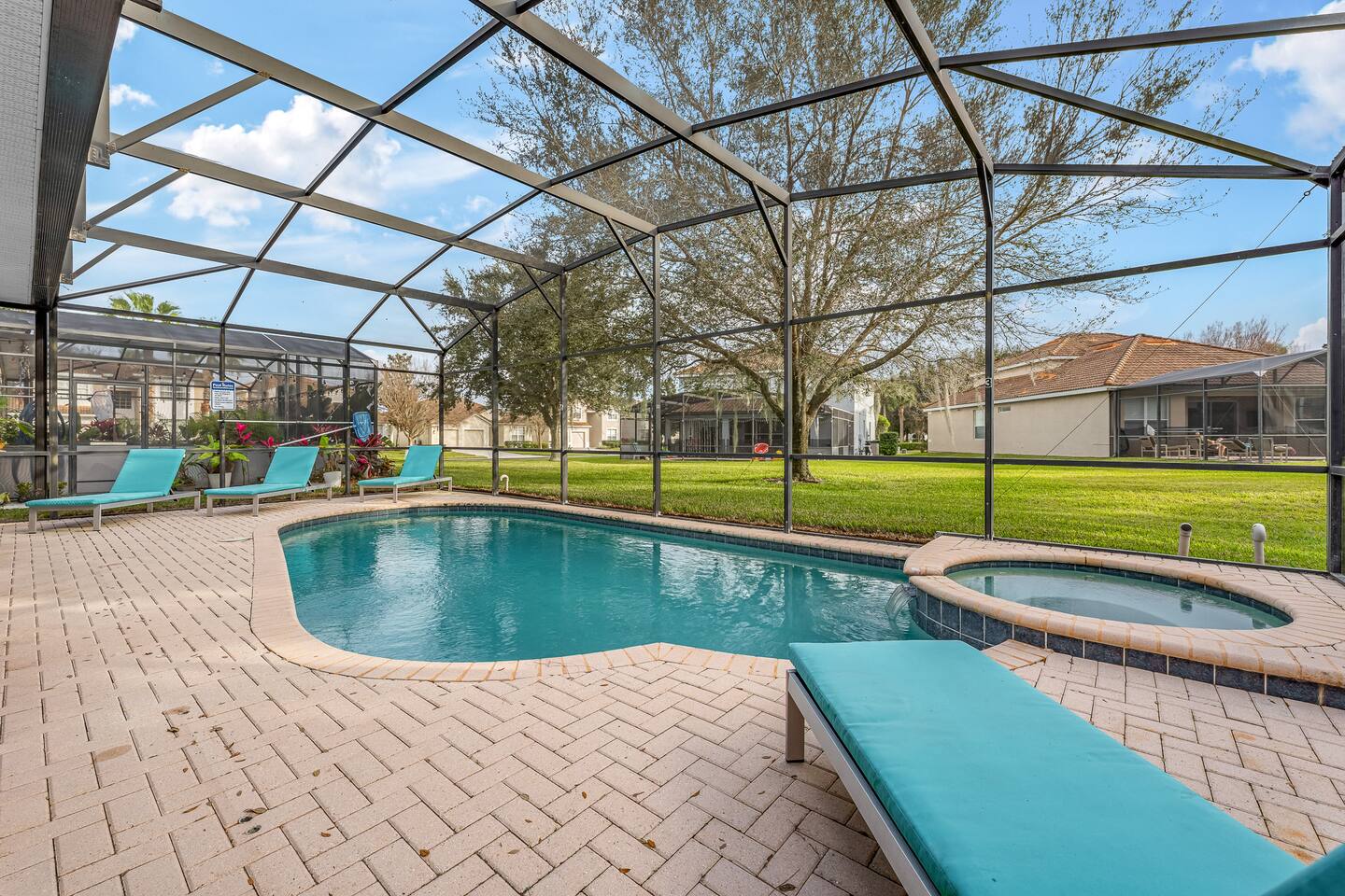 Pool and spillover spa inside the screened lanai, with plenty of loungers.