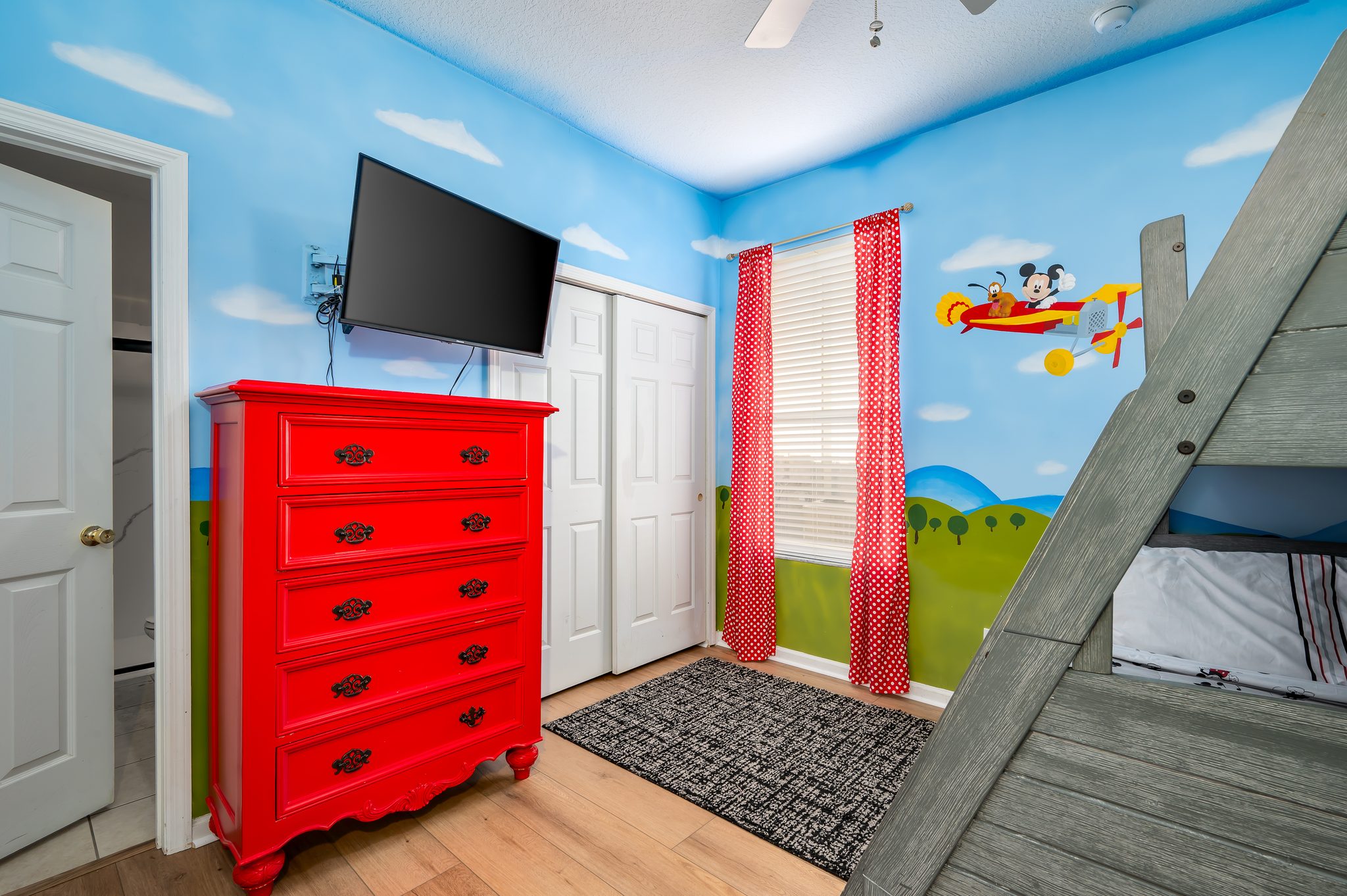 Mickey-themed kids room with bunk bed, TV, and mickey mural
