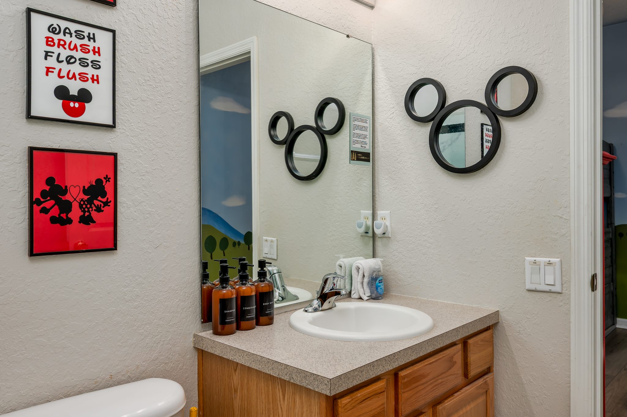 Mickey-themed bathroom with vanity, toiletries, and towels