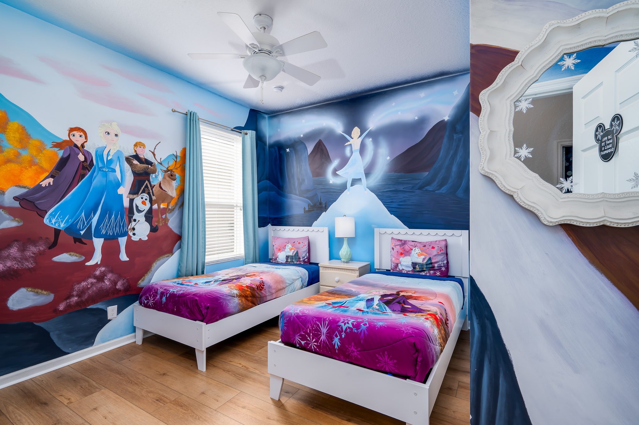 Frozen-themed kids’ room with twin beds, mural art, and bright charm