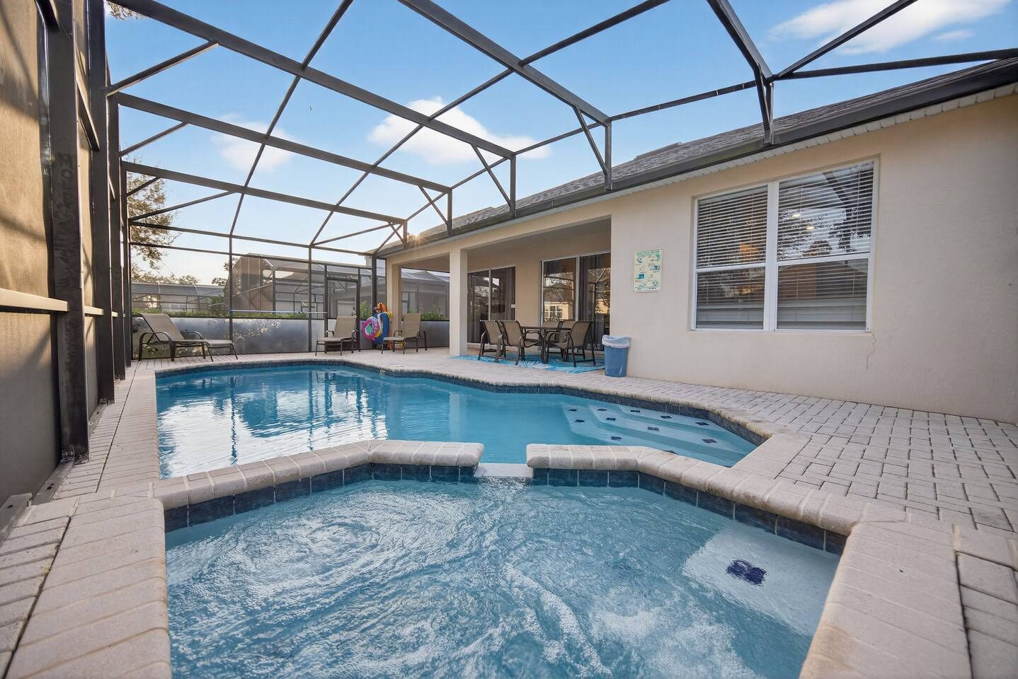 Wide view of the pool, spa, and covered lanai seating