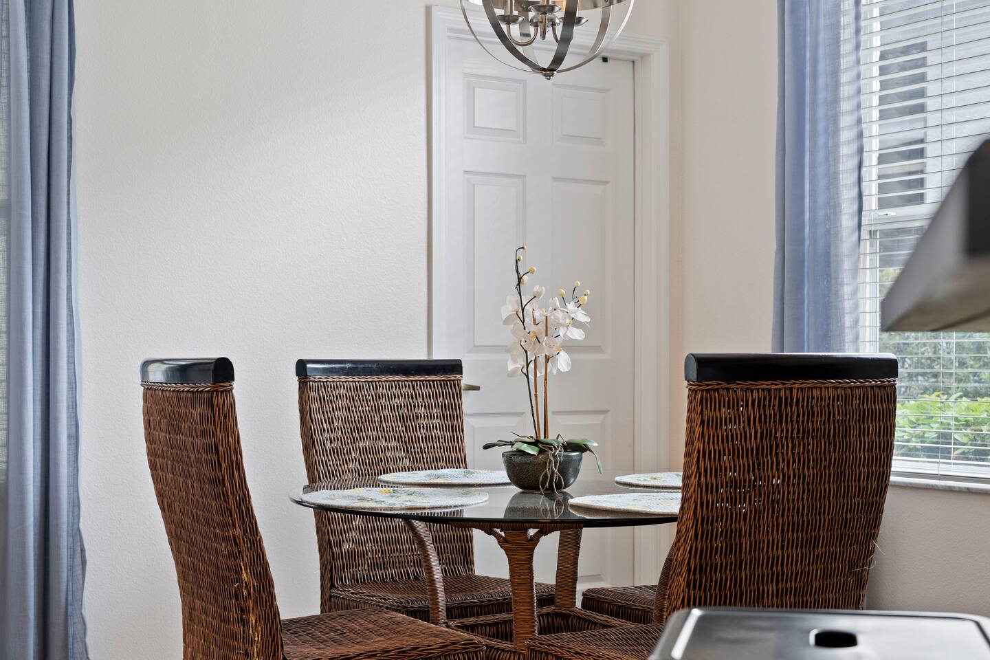 Enjoy meals at this stylish glass-top table surrounded by chic wicker chairs!