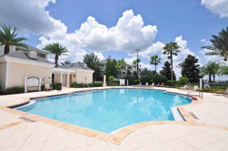 Sun-soaked resort community pool surrounded by palms and lounge seating