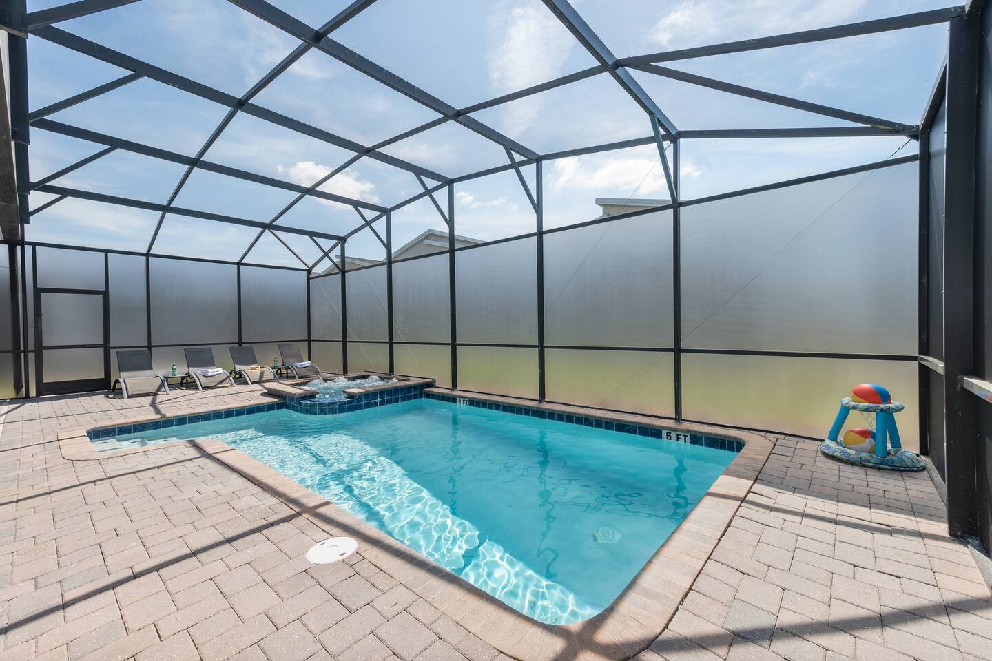 Screened private pool with spillover spa, sun loungers, and a floating basketbal