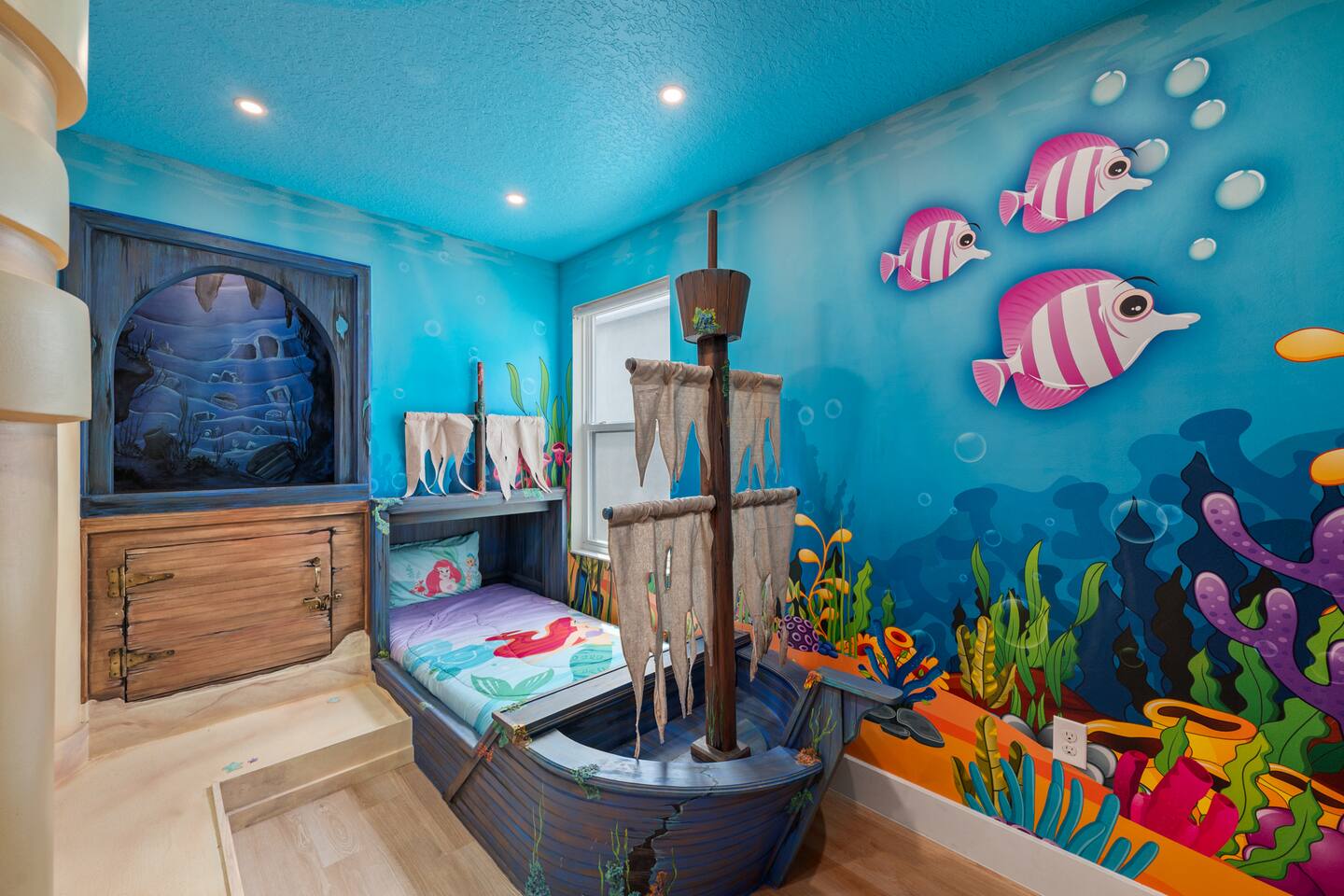 Pirate-ship bed beside a wooden hatch nook beneath a sea-cave mural in the Littl