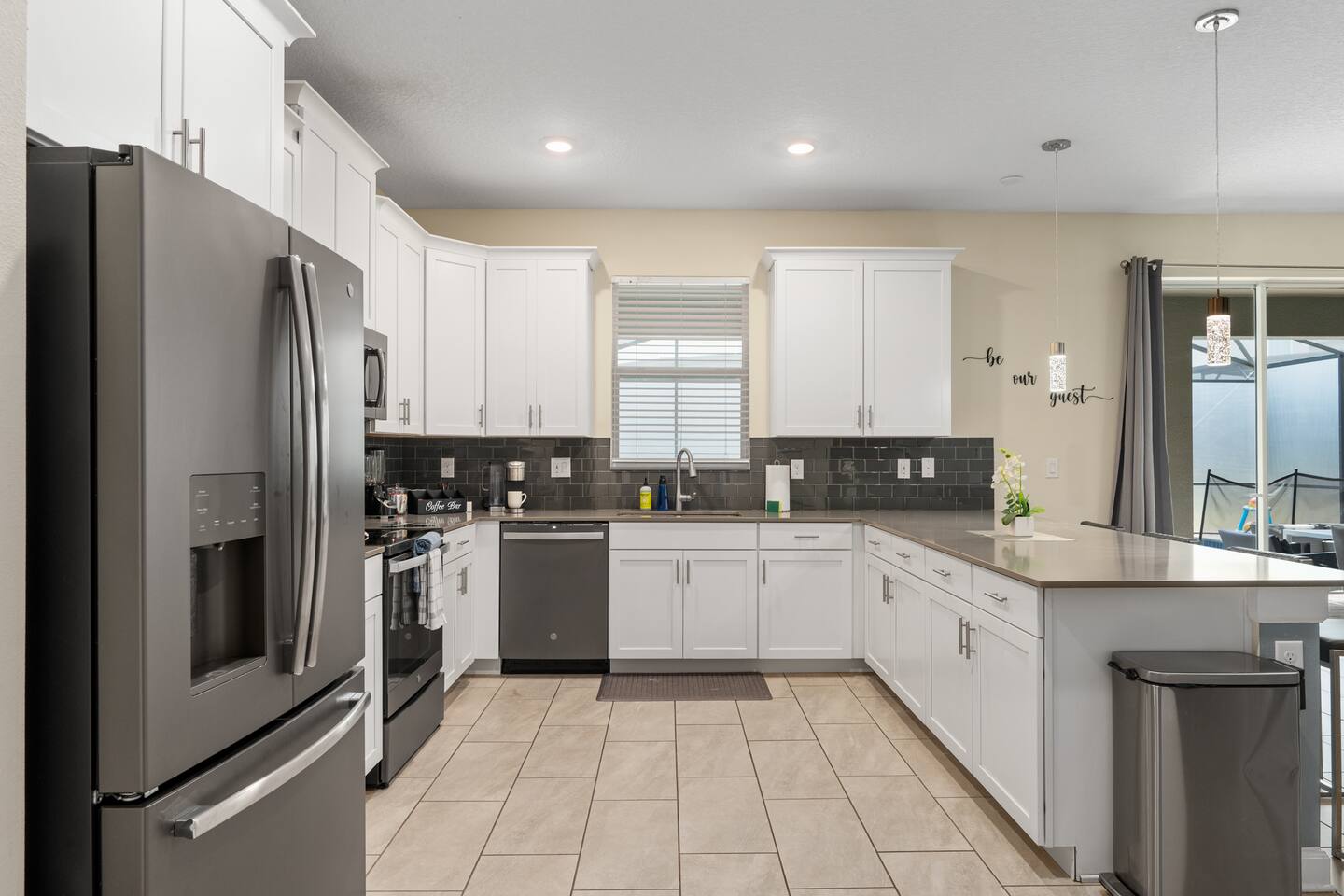 Kitchen with white cabinets, slate appliances, coffee bar, and dark subway-tile 