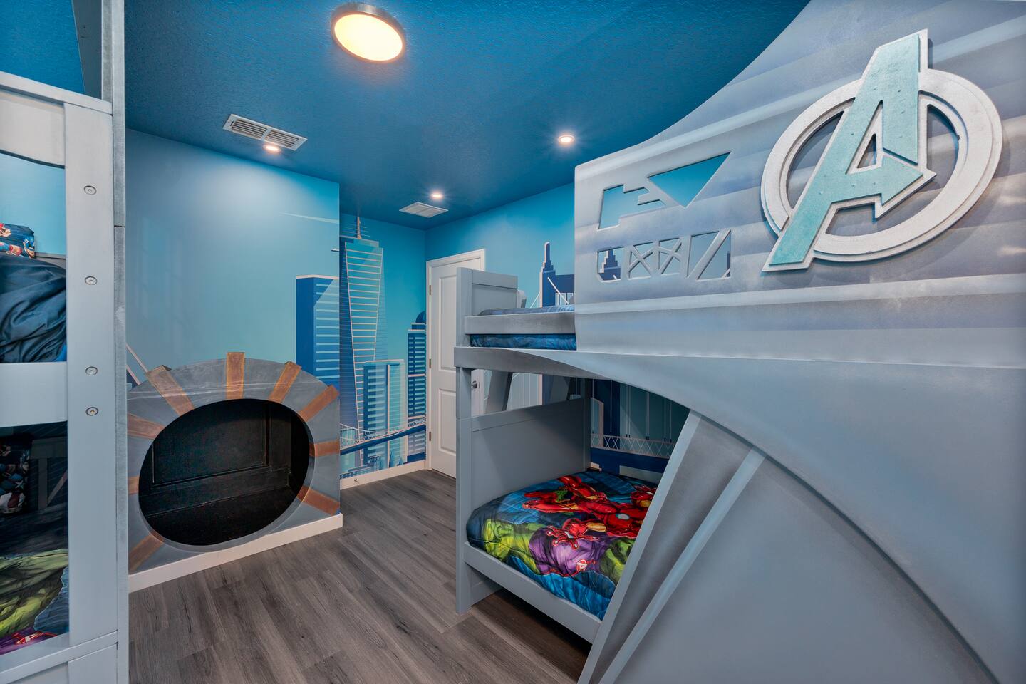 Avengers room bunks with superhero logo headboard, city mural, and tunnel entran