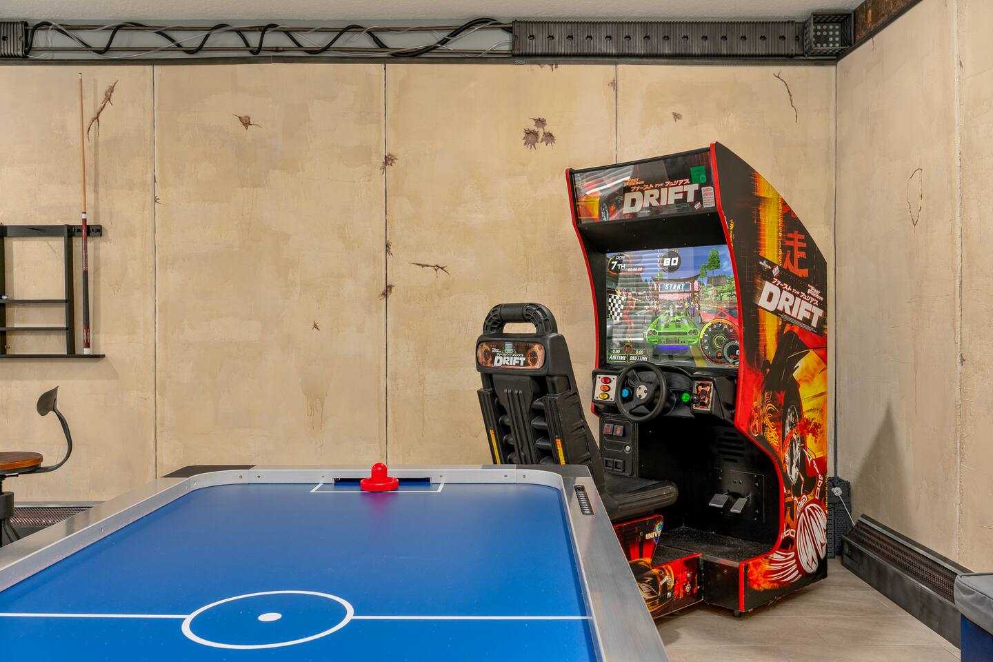 Air hockey table and sit-down racing arcade game in the game room