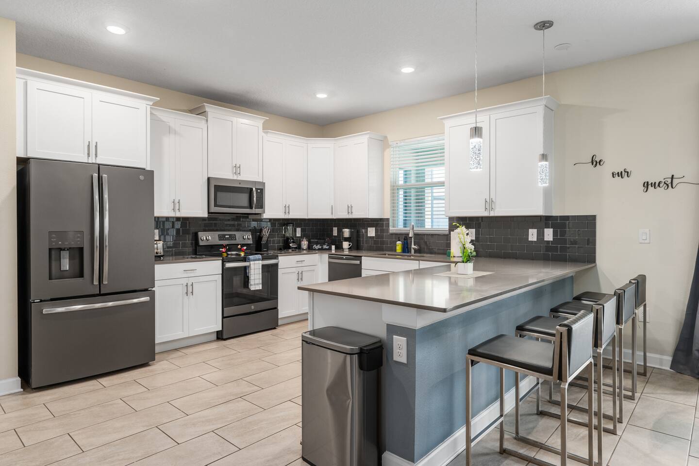 Kitchen breakfast bar with four stools and be-our-guest wall decor