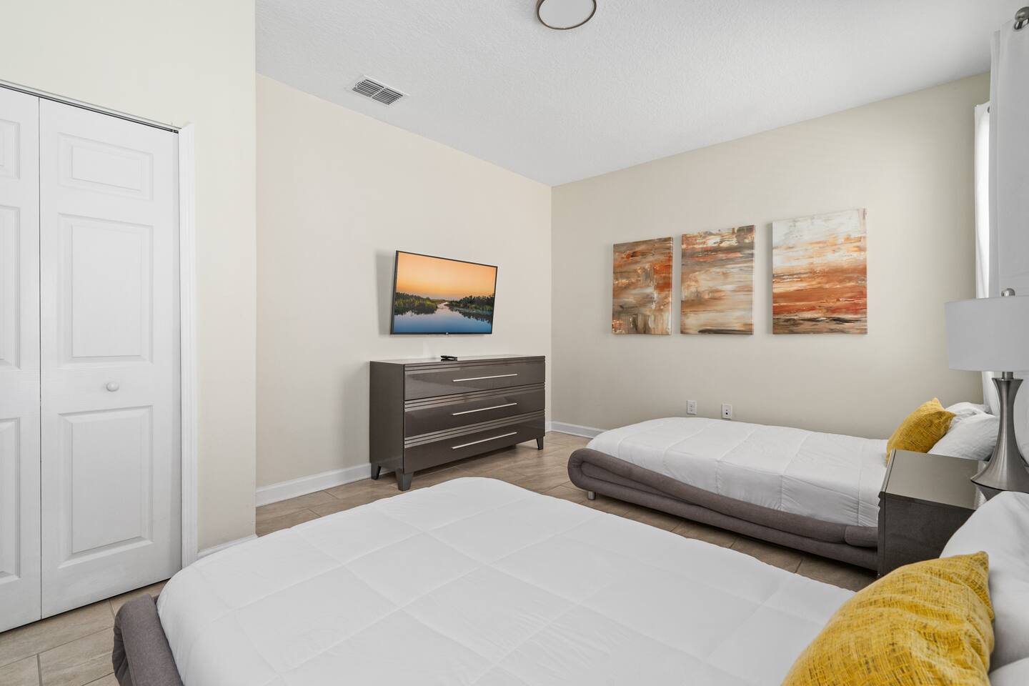 Main-floor bedroom with two full beds, dresser, and wall-mounted TV