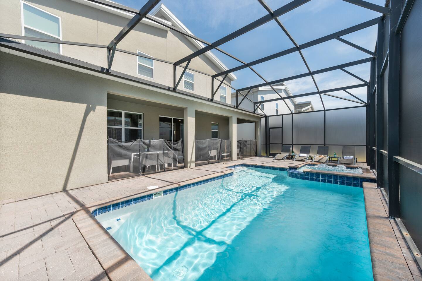 Screened pool deck with sun loungers, spa, and covered patio
