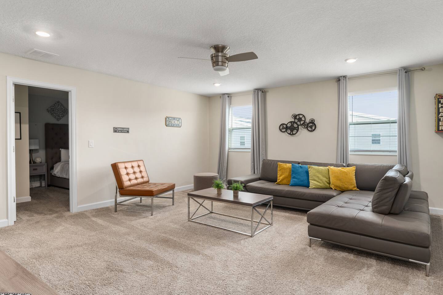 Loft movie lounge with sectional, leather accent chair, and film-reel wall art