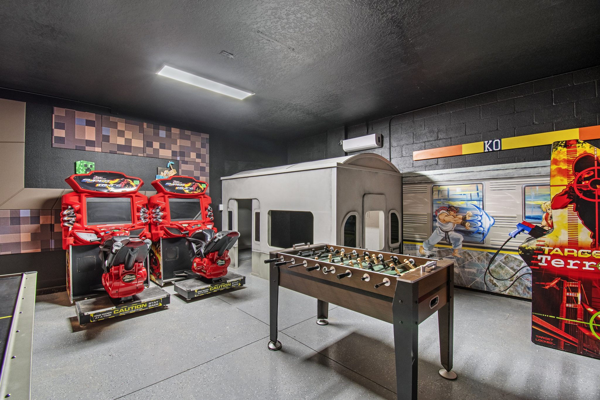 Game room with dual racing arcades, a foosball table, and an arcade shooter game