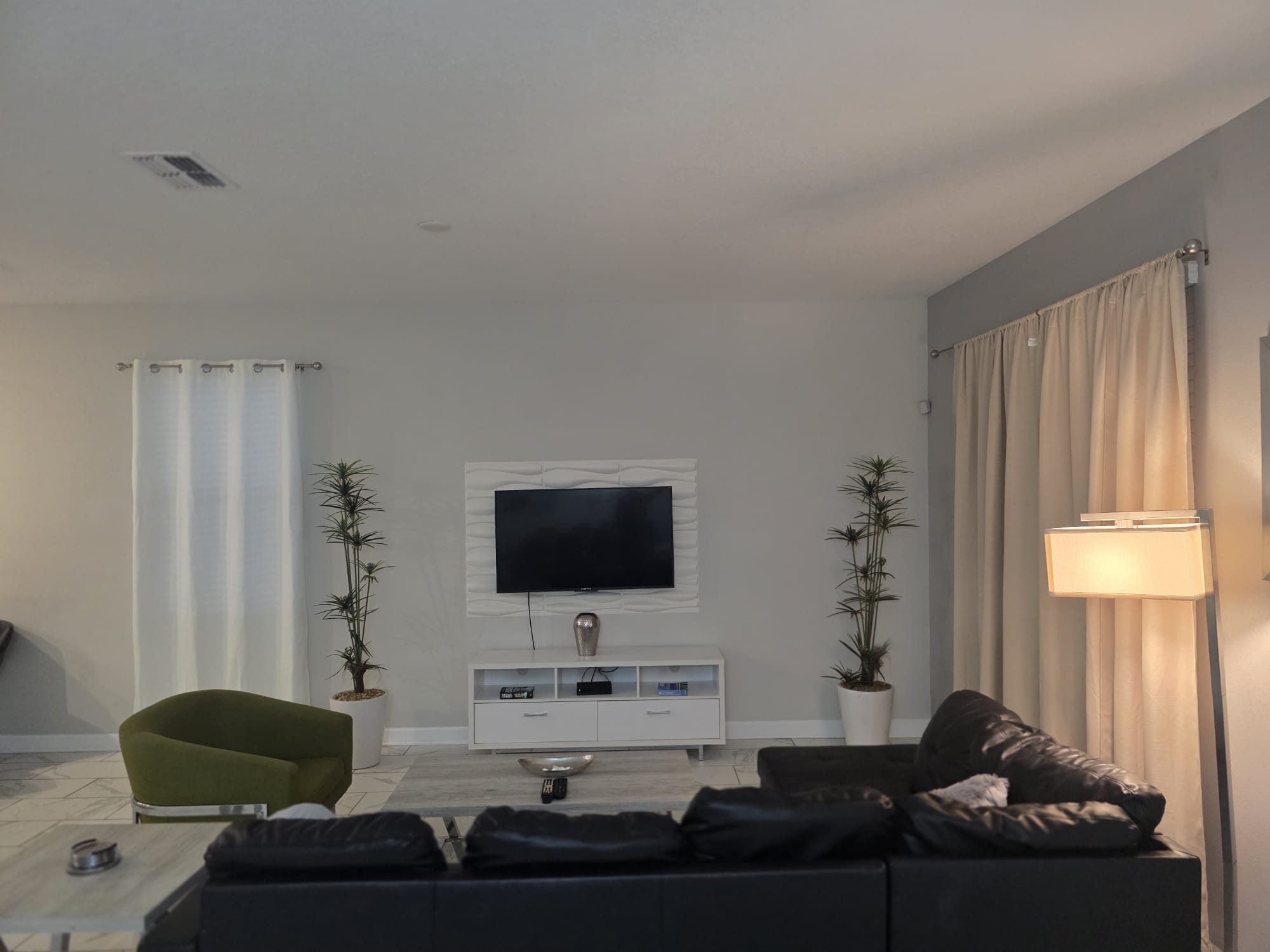 Living room with a leather sectional, accent chair, and wall-mounted TV